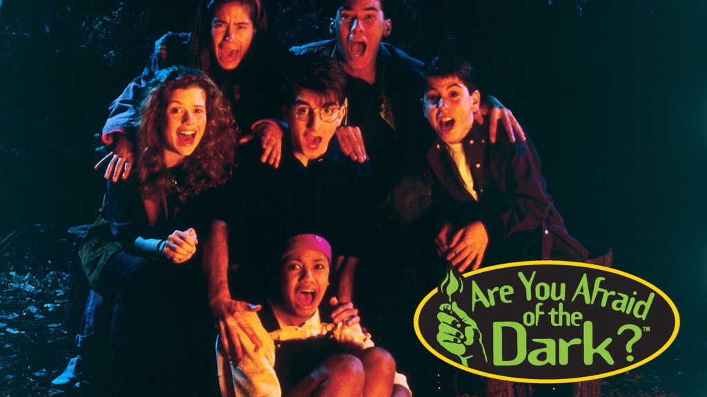 The cast of Are you Afraid of the Dark? in front of their campfire, frightened